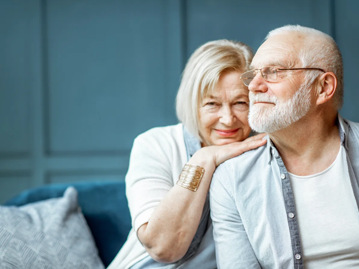 Two people sit close together on teal couch, both wearing light-colored tops
