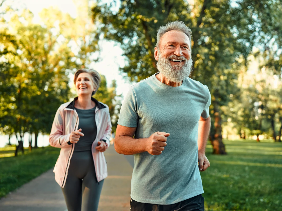 Two people walking on a paved path in a park with trees