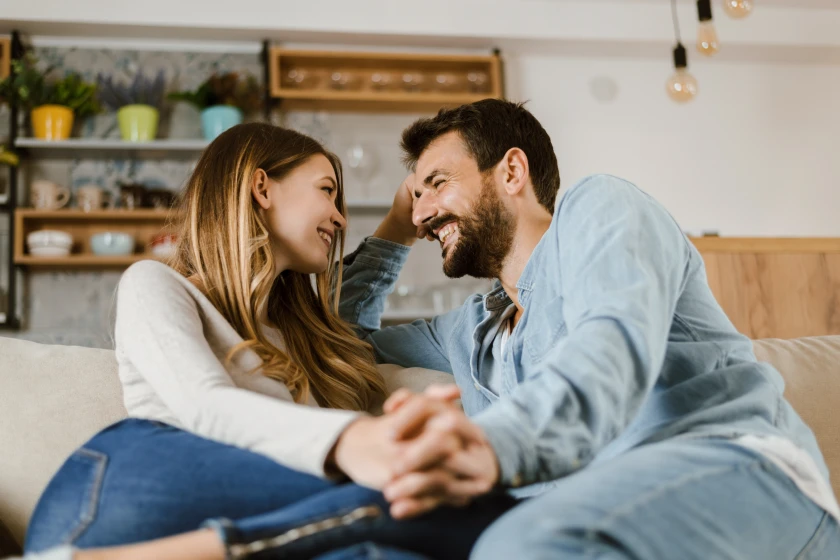 Two people sit close together on blue couch, one wearing denim shirt