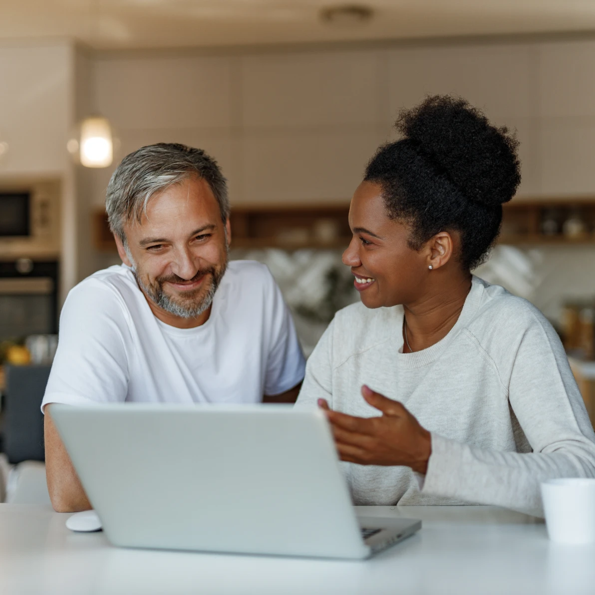 Two people sitting at table looking at laptop computer indoors