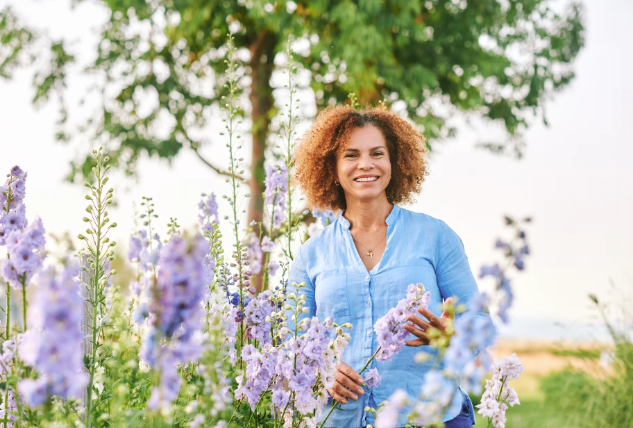 Person in blue cardigan standing in garden with purple flowering plants